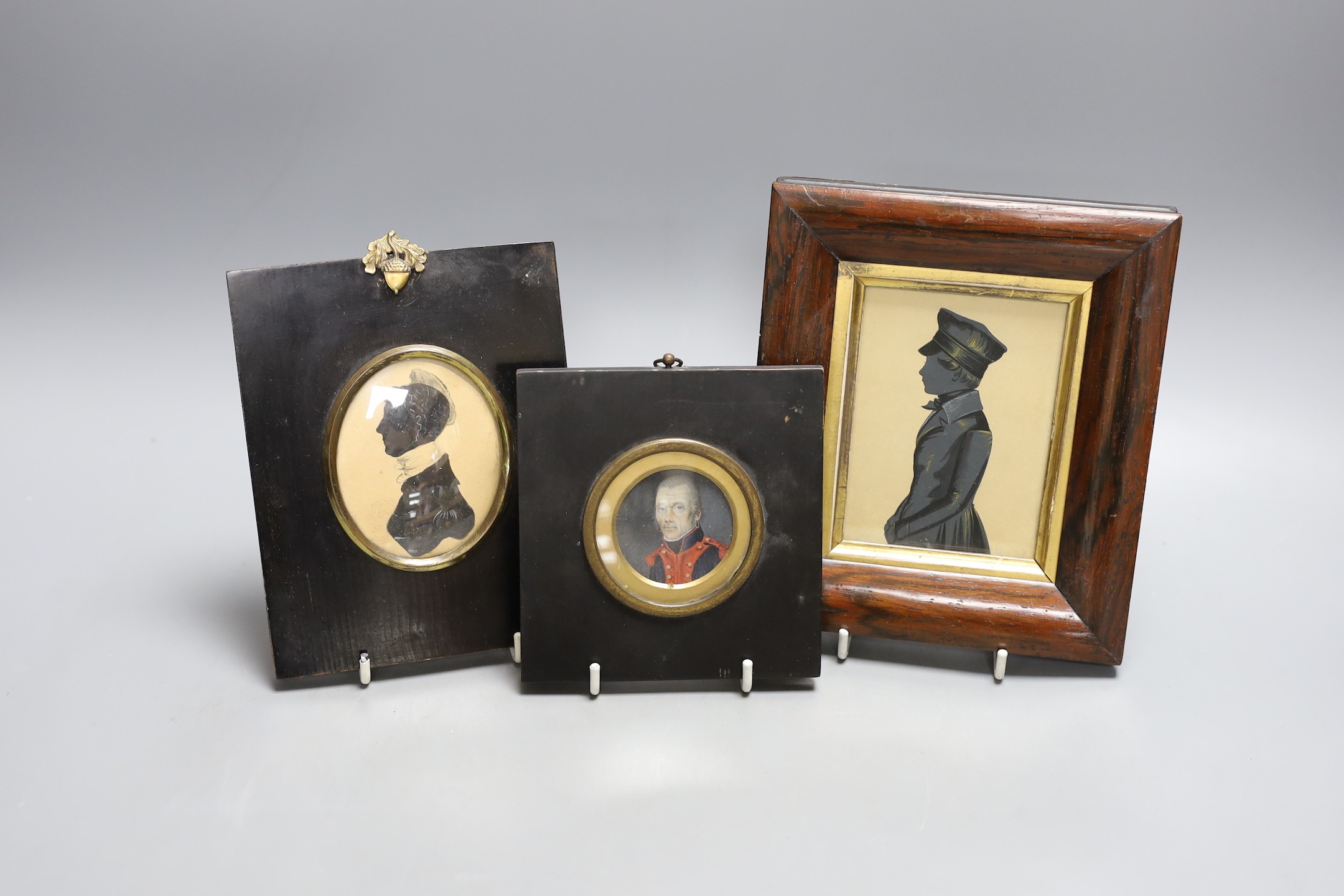 An unusual portrait miniature of a 19th century gentleman wearing earrings, together with two framed silhouettes (3)